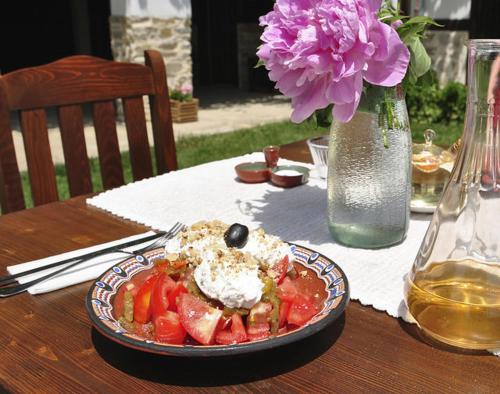 a plate of food on a table with a vase of flowers at Osmarski Houses in Osmar