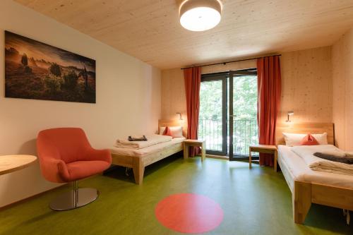 a room with two beds and a chair and a window at Hotel 11 Eulen in Uelzen