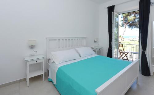Habitación blanca con cama y balcón. en Addore Re Mare en Santa Maria di Castellabate