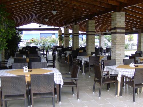 an empty restaurant with tables and chairs and tablesktop at Hotel Lefkes in Paralía Skotínis