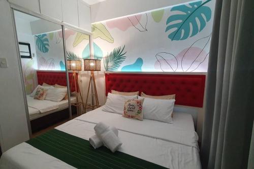 a bedroom with a large bed with a red headboard at Tropical Escape at Cedar Crest in Manila