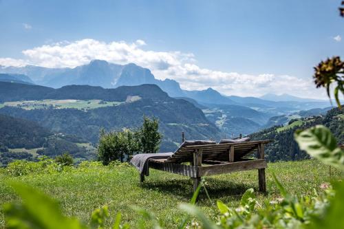 a bench sitting on top of a hill with mountains at HAUSERHOF - Urlaub auf dem Bauernhof in Villandro