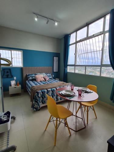 a bedroom with a bed and a table and chairs at GUARALOFT ARUBA NO MIRANTE DE GUARAPARI in Guarapari