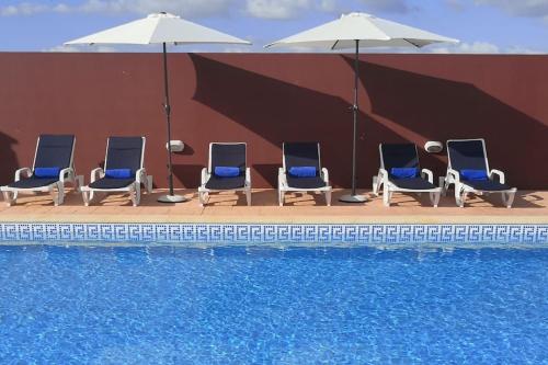 a group of chairs and umbrellas next to a pool at JOHN's Farm Country HOUSE in Montemor-o-Novo