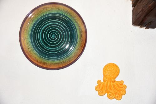 a green glass plate hanging on a wall with an orange object at Splendida villa in riva al mare in Orosei