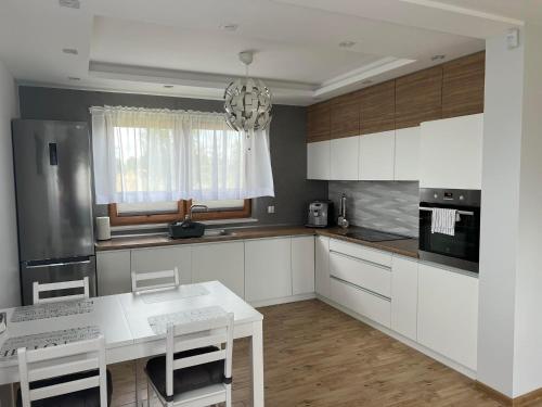 a kitchen with white cabinets and a chandelier at Beztroski Zakątek in Nowe Guty
