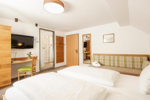 a bedroom with a large white bed and a desk at Landhotel Stofflerwirt in Sankt Michael im Lungau