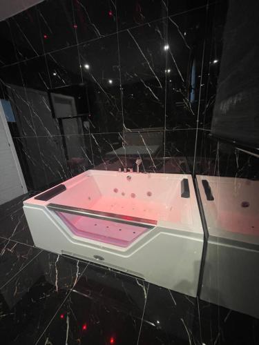 a pink bath tub in a black tiled bathroom at Life Hotel in Casalnuovo di Napoli