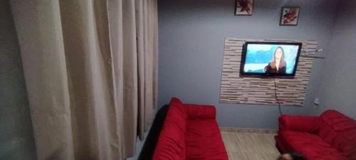 ein Wohnzimmer mit einem roten Sofa und einem Flachbild-TV in der Unterkunft Casa de Boneca aconchegante in Uberaba