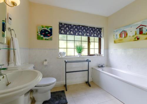 a bathroom with a tub and a toilet and a sink at Oak Cottage in Dulverton