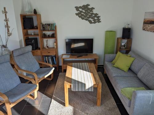uma sala de estar com um sofá e cadeiras e uma televisão em Ferienwohnung Pappelwende em Ostseebad Karlshagen