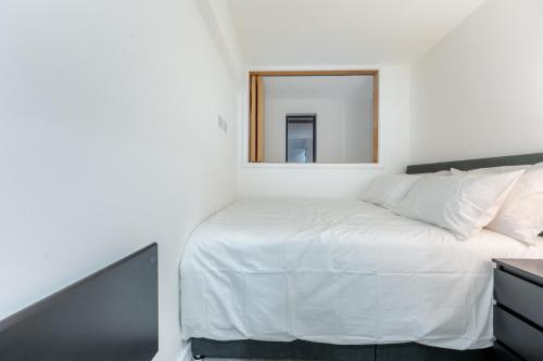 um quarto com uma cama branca e um espelho em Stunning 2BD Apartment in Manchester em Manchester
