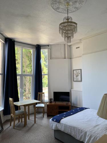 a bedroom with a bed and a table and a chandelier at Ensuite Double Room, by Swansea University, Sketty, R2 in Swansea