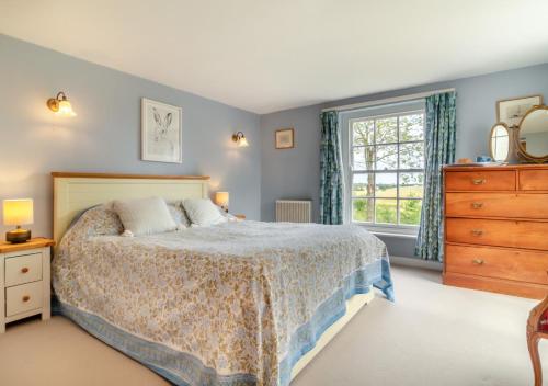 a bedroom with a bed and a dresser and a window at Three Ash Farm in Bungay