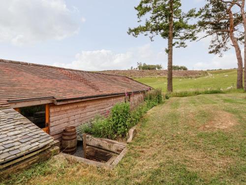 an old barn with a field and trees in the background at Y Caban in Llangollen