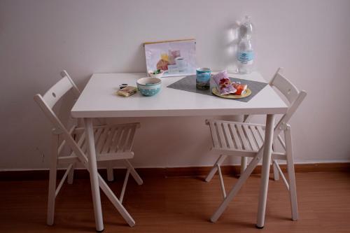 una mesa blanca con 2 sillas y un plato de comida en B&B Villa Susanna, en Civitavecchia