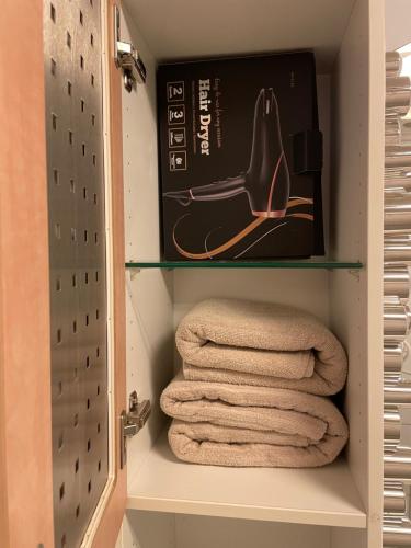 un armario con toallas y una caja en un estante en Lovely condo with fireplace & parking@city center en Drammen
