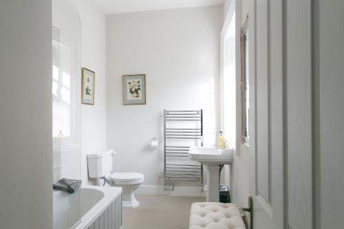 baño blanco con bañera, aseo y lavamanos en Stay On The Hill - The Coach House en Hexham