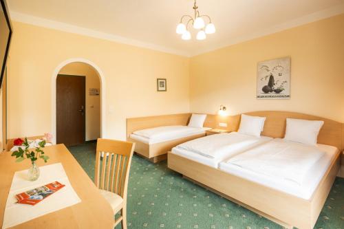 a hotel room with two beds and a table at Landhotel Stofflerwirt in Sankt Michael im Lungau