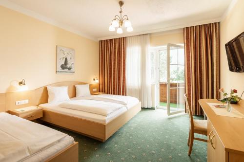 ザンクト・ミヒャエル・イム・ルンガウにあるLandhotel Stofflerwirtのベッド2台と窓が備わるホテルルームです。