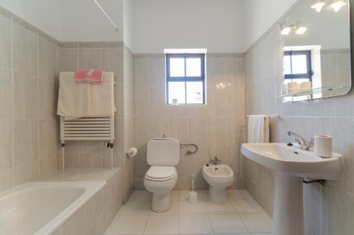 a white bathroom with a toilet and a sink at Villa Eucalipto in Lagoa