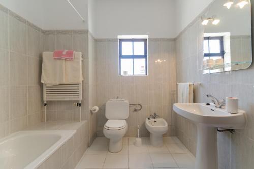 a white bathroom with a toilet and a sink at Villa with Private Pool Near Benagil & Marinha Beach in Lagoa