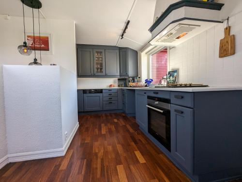 a kitchen with blue cabinets and a wooden floor at Sea & Mountain View Apartment Tromsø in Tromsø