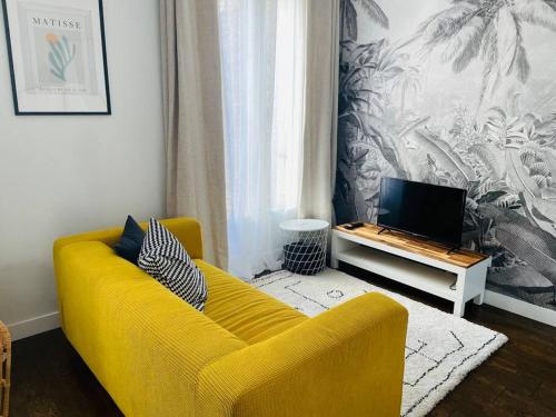 een woonkamer met een gele bank en een televisie bij Comme à la maison-Porte de Paris in Pantin