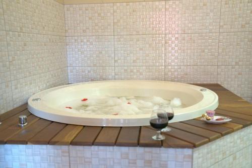 a bath tub with a glass of wine in a bathroom at Pousada Recanto dos Pássaros in Visconde De Maua