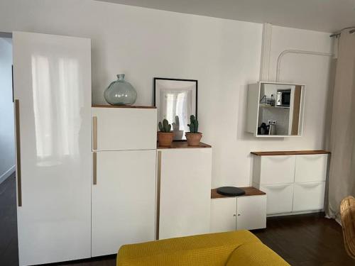 a living room with white cabinets and a yellow couch at Comme à la maison-Porte de Paris in Pantin