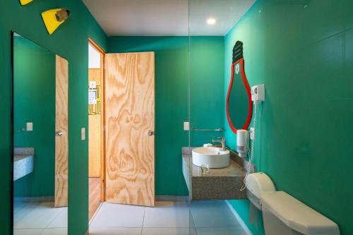 a green bathroom with a sink and a mirror at Mayan Monkey Cancun in Cancún