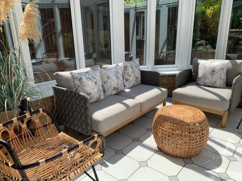a porch with a couch and chairs on a patio at Virginia Water Family getaway in Virginia Water