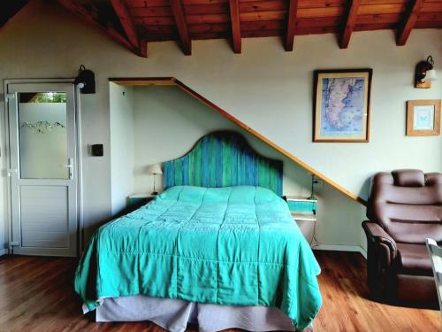 een slaapkamer met een groen bed en een stoel bij Puerto Esmeralda ESPECTACULAR DEPTO CON VISTA AL LAGO NAHUEL HUAPI in Villa La Angostura