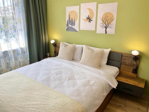 a bedroom with a white bed and some paintings on the wall at Colourful Apartment for 4 Guests and Free Parking in Stara Zagora