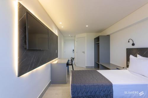 a hotel room with a bed and a flat screen tv at Slaviero João Pessoa in João Pessoa