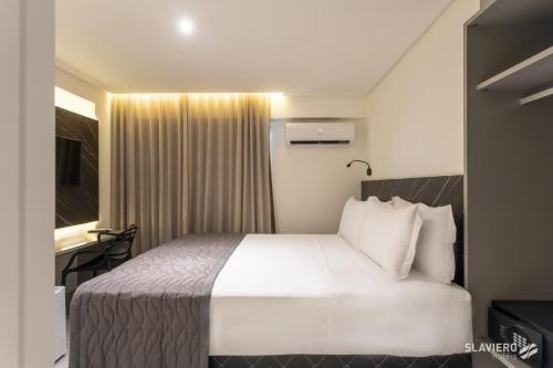 a hotel room with a white bed and a desk at Slaviero João Pessoa in João Pessoa