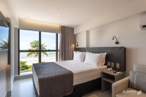 um quarto de hotel com uma cama e uma grande janela em Arpoar Suítes by Slaviero Hotéis em João Pessoa