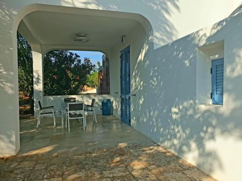 Casa blanca con patio con mesa y sillas en Trullollero UnPostoNelMondo, en Ceglie Messapica