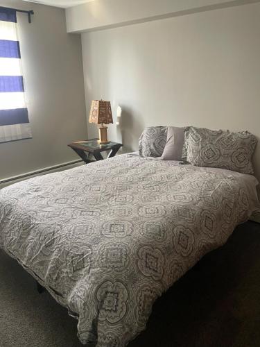 a bedroom with a bed and a lamp and a window at One Bedroom Main floor Apartment in Camrose