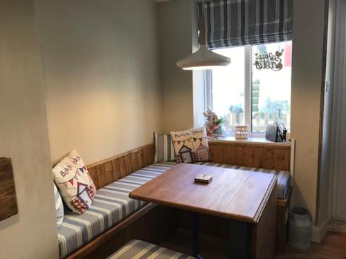 a room with a bench with a table and a window at The Blue Porch Staithes in Staithes