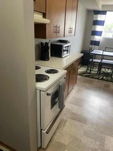 a kitchen with a white stove and a microwave at One Bedroom Main floor Apartment in Camrose
