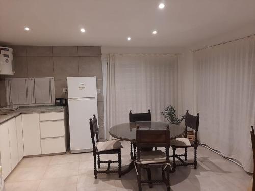 eine Küche mit einem Tisch und Stühlen sowie einem weißen Kühlschrank in der Unterkunft Alquiler por día Bahía Blanca in Bahía Blanca