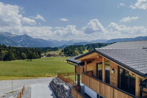 a house with a view of a field and mountains at Platzhirsch Ofterschwang in Ofterschwang
