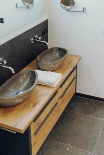 two sinks on a wooden counter in a bathroom at Platzhirsch Ofterschwang in Ofterschwang