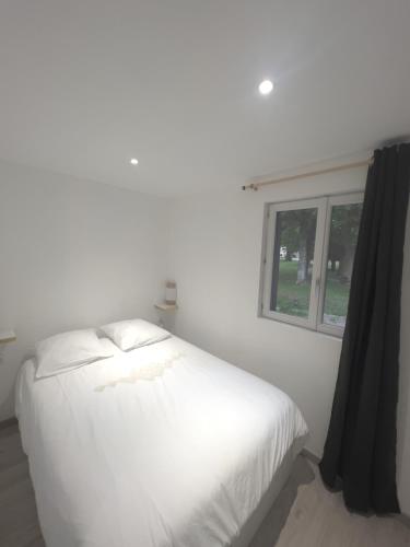 un lit blanc dans une chambre avec une fenêtre dans l'établissement Au domaine des roches, à Saint-Pierre-sur-Dives