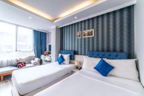 2 łóżka w pokoju hotelowym z niebieskimi akcentami w obiekcie Ruby Saigon Hotel - Ben Thanh w Ho Chi Minh