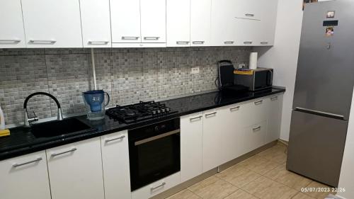 uma cozinha com armários brancos e um balcão preto em Natural House em Constança