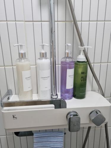 a shelf with four bottles on it in a bathroom at Mia House in Daegu