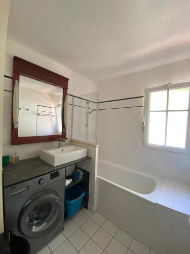 La salle de bains est pourvue d'un lave-linge, d'un lavabo et d'une baignoire. dans l'établissement Maison à Lacanau Océan classée 2 étoiles, à Lacanau-Océan