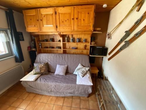 Cette chambre comprend un petit canapé et des placards en bois. dans l'établissement Studio à La Chapelle-d'Abondance proche centre et domaine skiable, Multi Pass été à 3€/jour/personne - FR-1-692-85, à La Chapelle-dʼAbondance